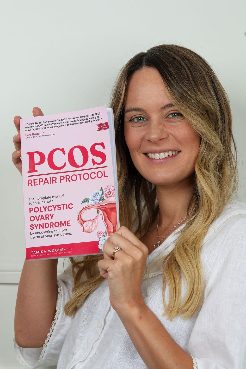 Tamika Woods holding the PCOS Repair Protocol book